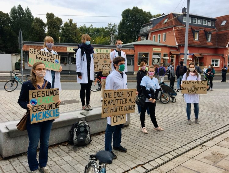 mehrere Personen mit weißem Arztkittel demonstrieren für Klimaschutz. Auf ihren Schildern steht: gesunde Erde gesunde Menschen, Die Erde ist kaputter als die Hüfte deiner Oma